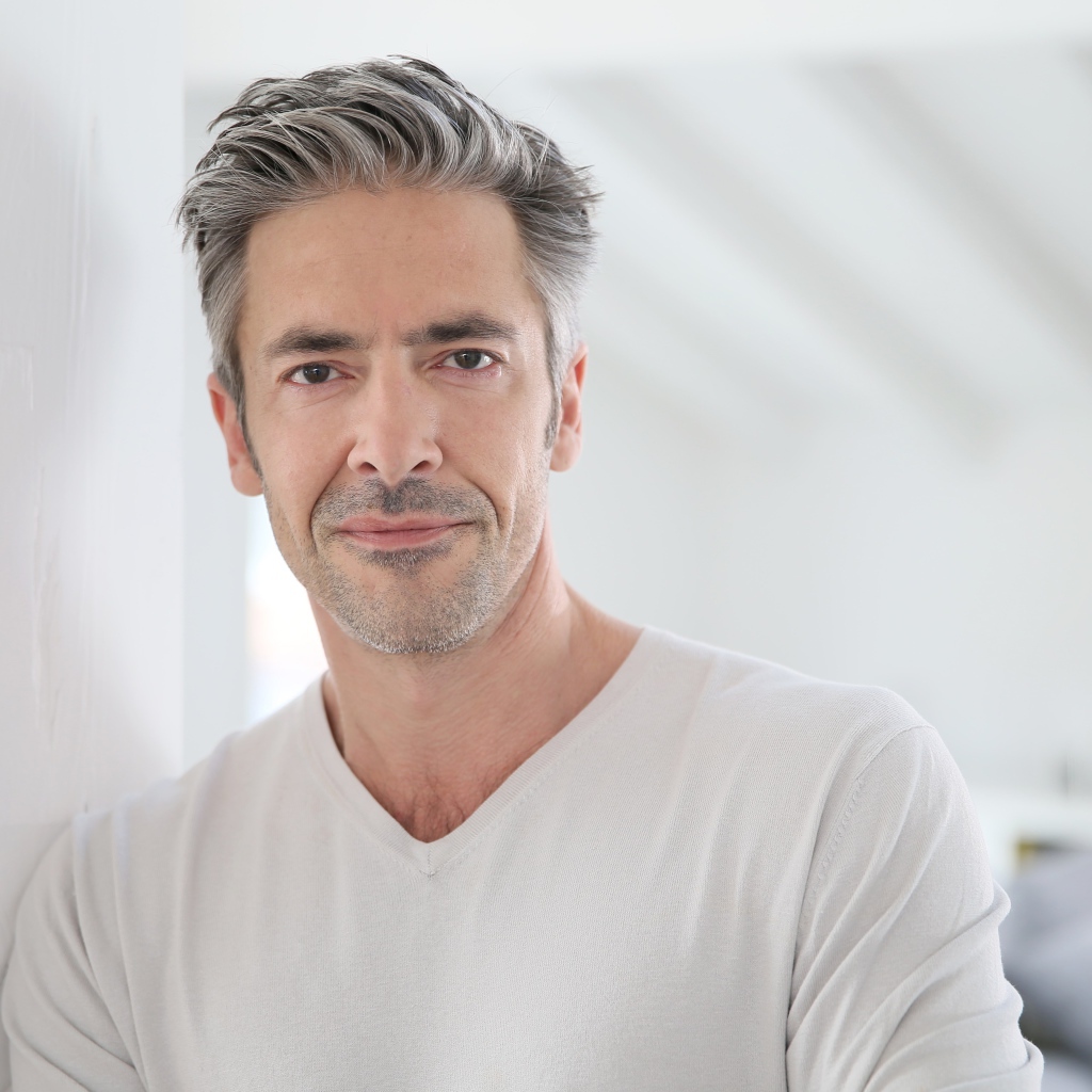 Седой стильный мужчина у стены