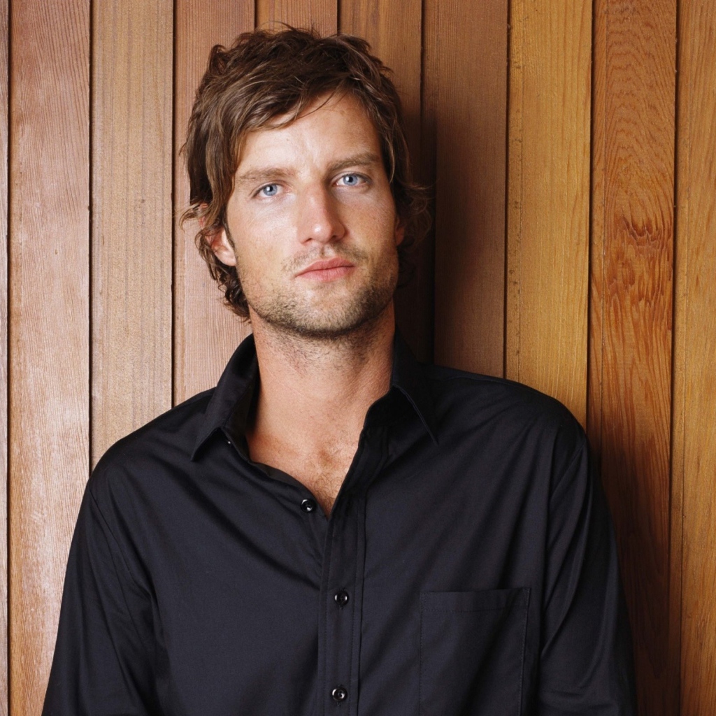 Красивый мужчина в черной рубашке на деревянном фоне