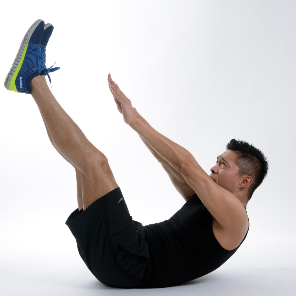 Мужчина спортсмен качает пресс на белом фоне