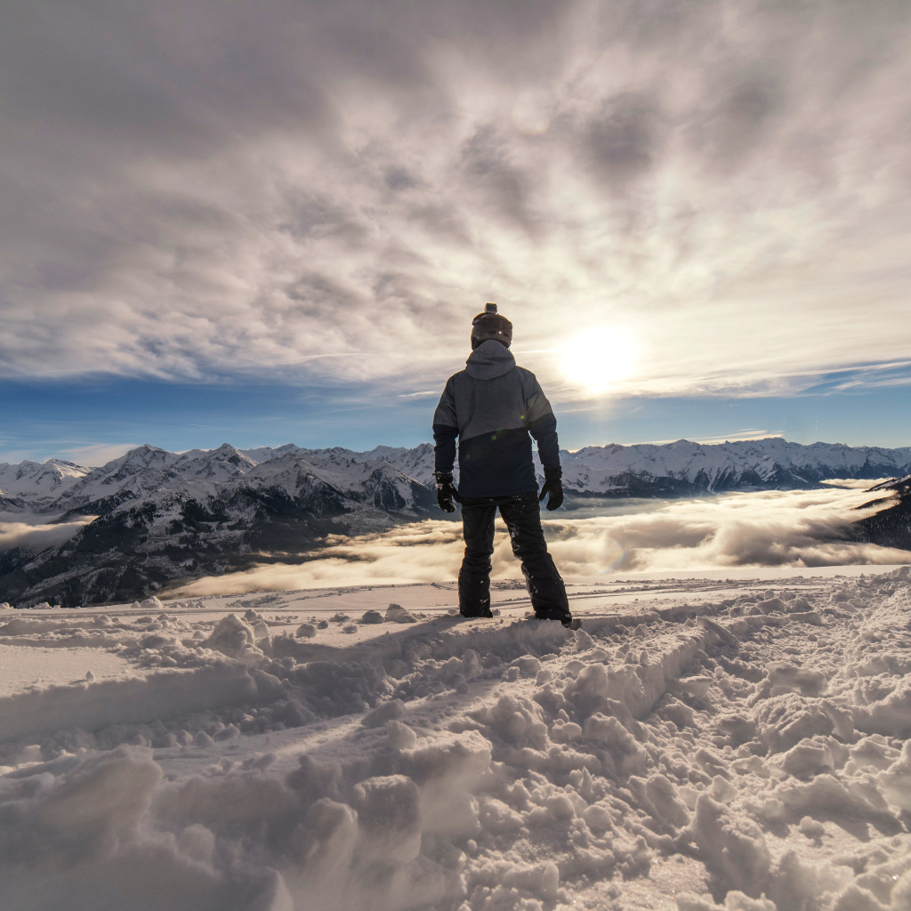 Человек в заснеженных горах в лучах солнца