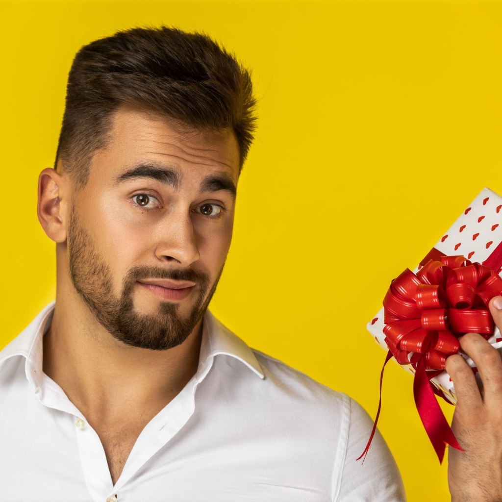 Мужчина с подарком на желтом фоне 