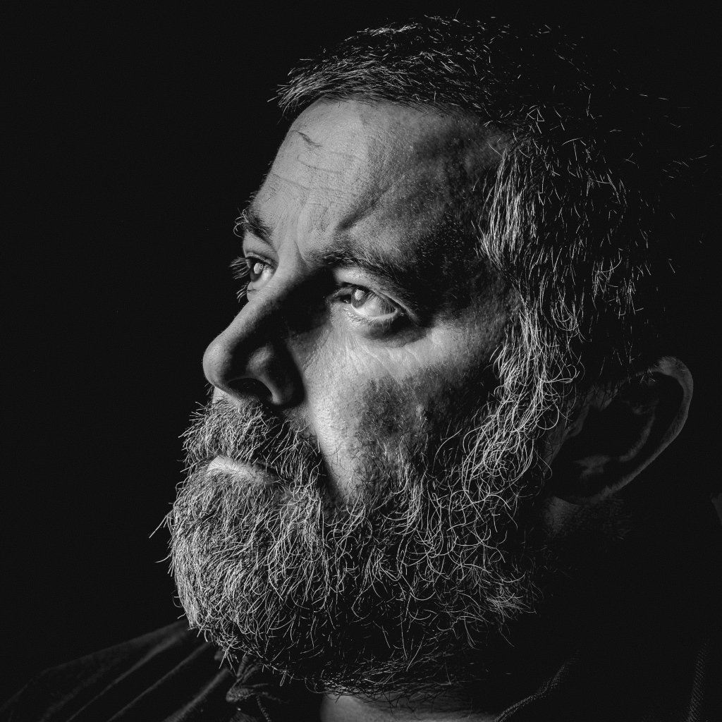 Мужчина с седой бородой на черном фоне 