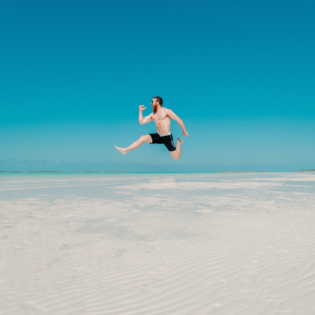 Довольный мужчина прыгает в воде на голубом фоне 