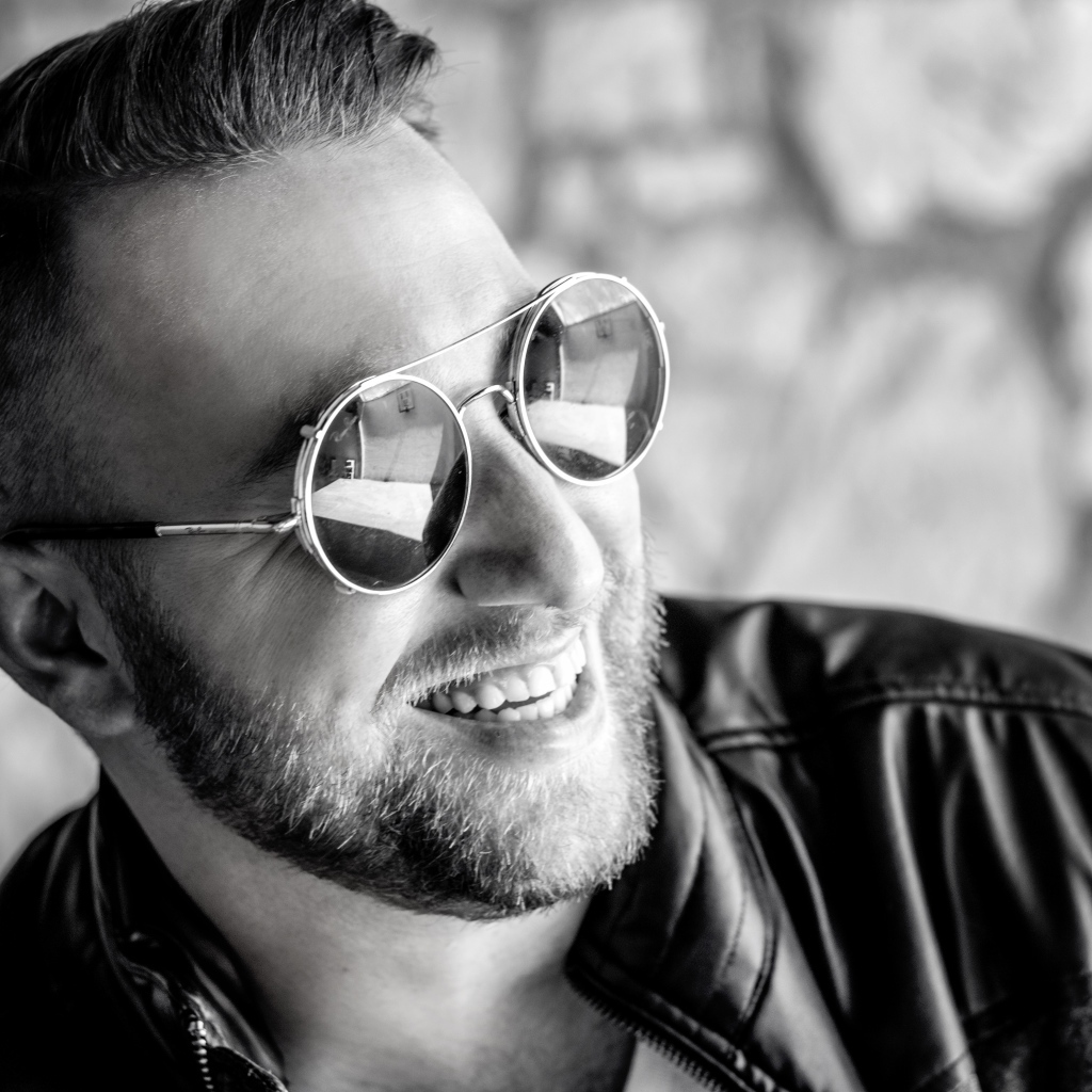 Улыбающийся брутальный мужчина в черных очках