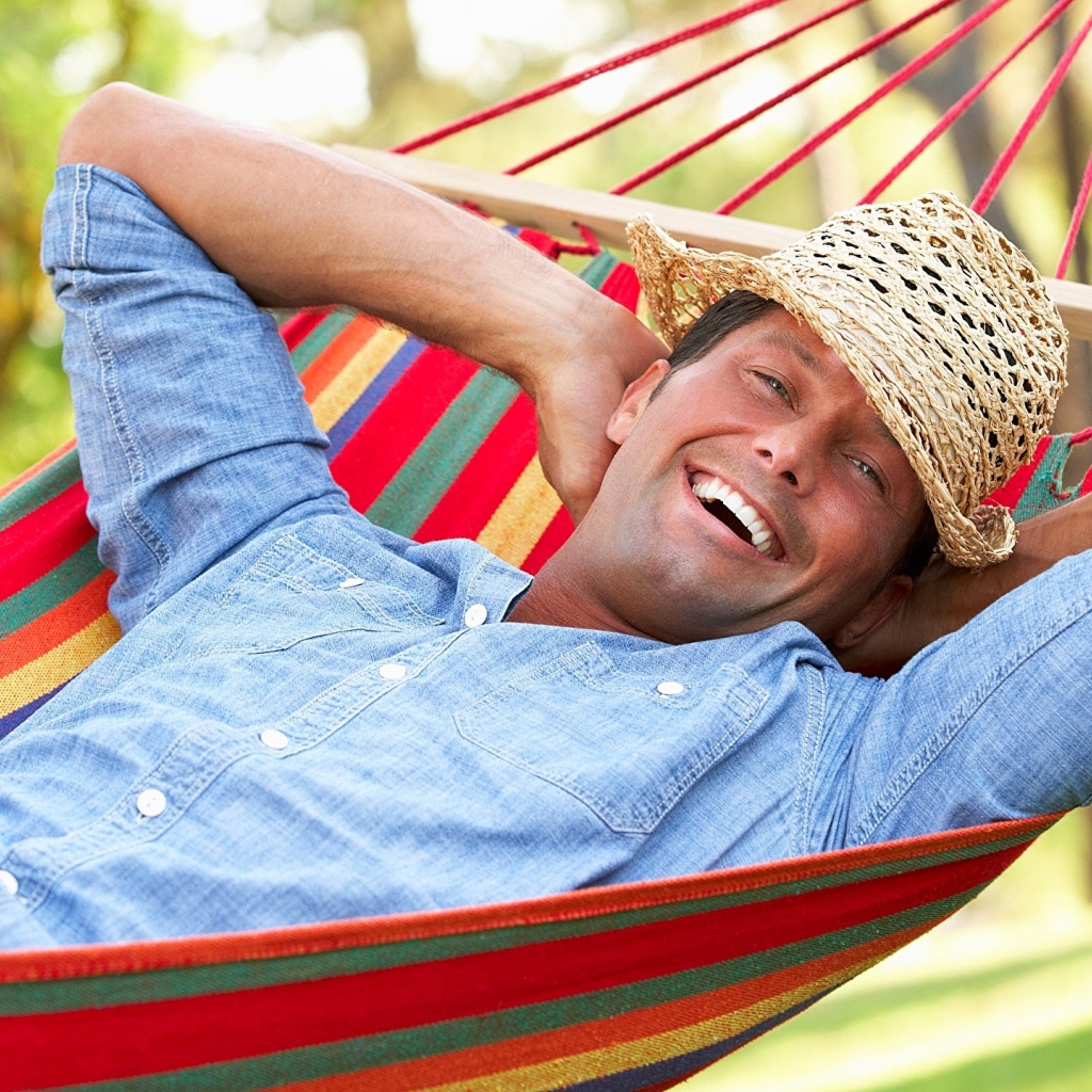 Улыбающийся мужчина спит в гамаке