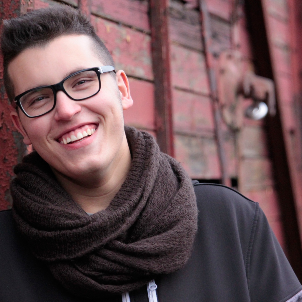 Улыбающийся мужчина в очках у стены 