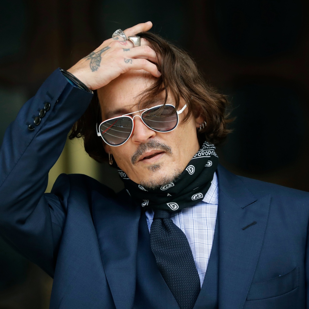 Актер Джонни Депп в очках с татуировками на руке