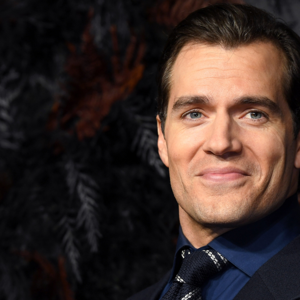 Улыбающийся актер Генри Кавилл в костюме