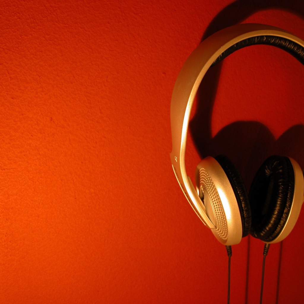 Большие золотые наушники на оранжевом фоне 