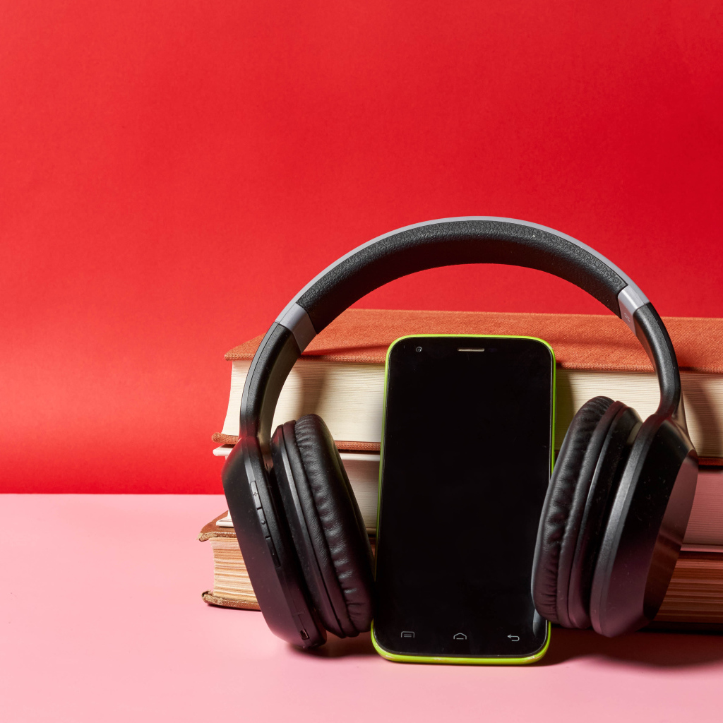 Смартфон, наушники и книги на красном фоне