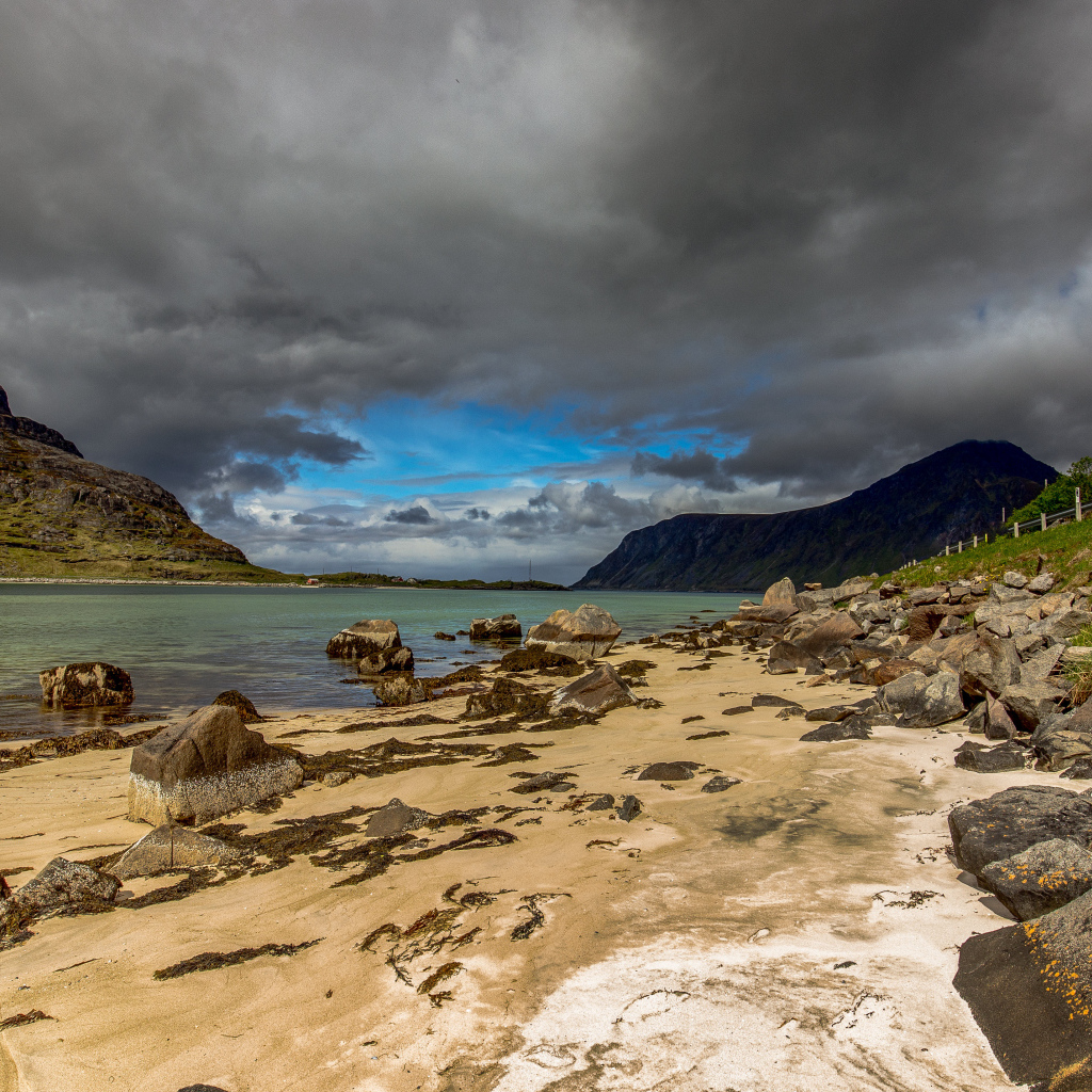 Большие камни на берегу фьорда под грозовым небом 