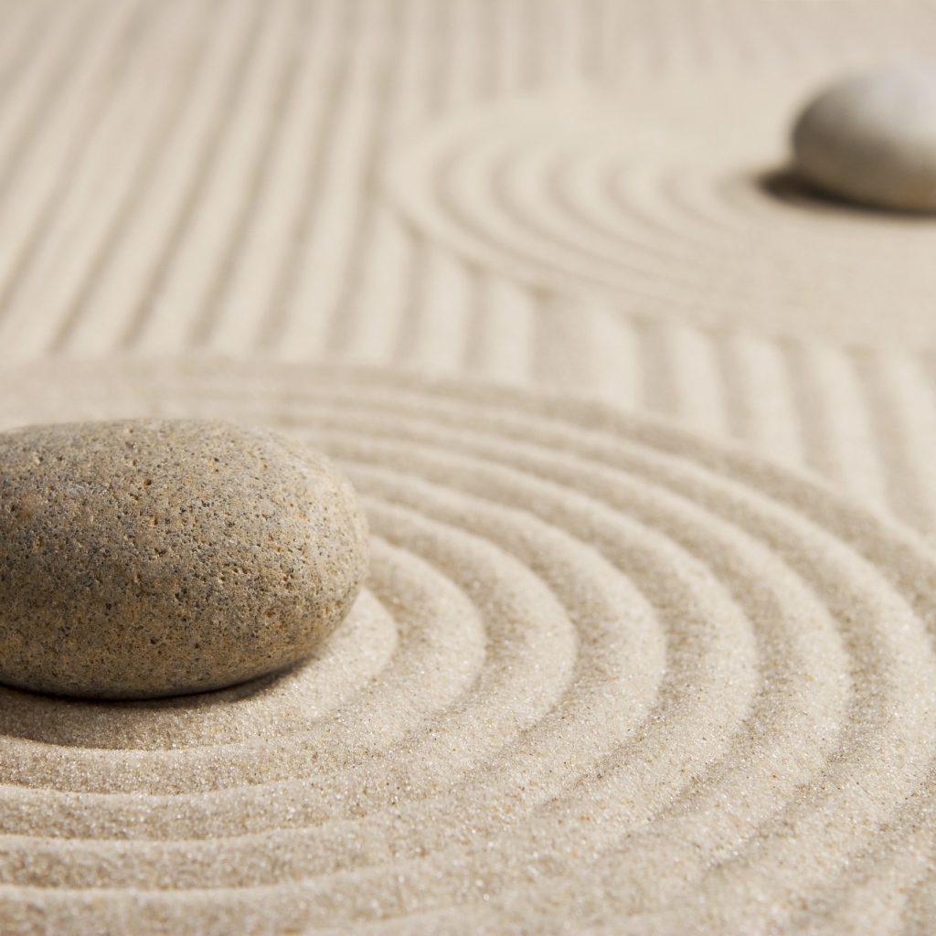 Большой серый камень на песке с кругами 