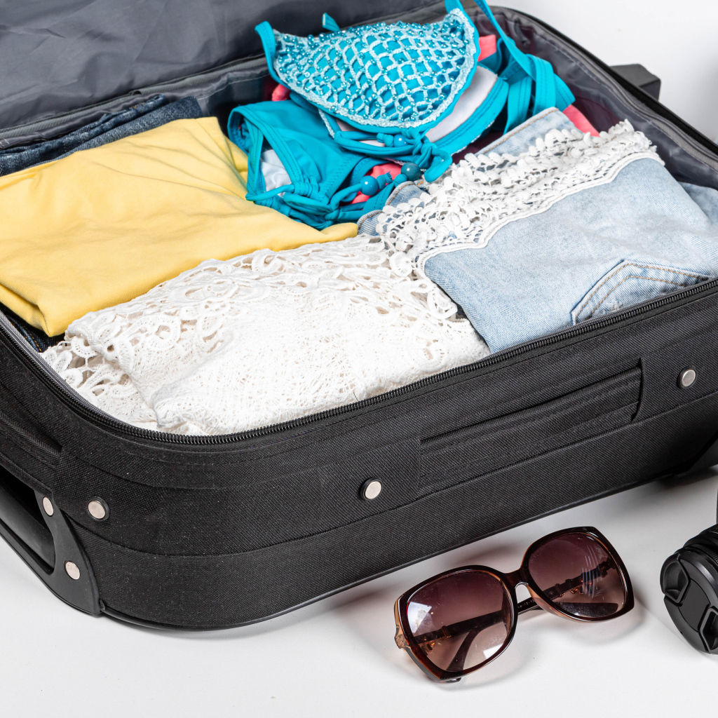 Чемодан с вещами для отпуска с фотоаппаратом и очками 