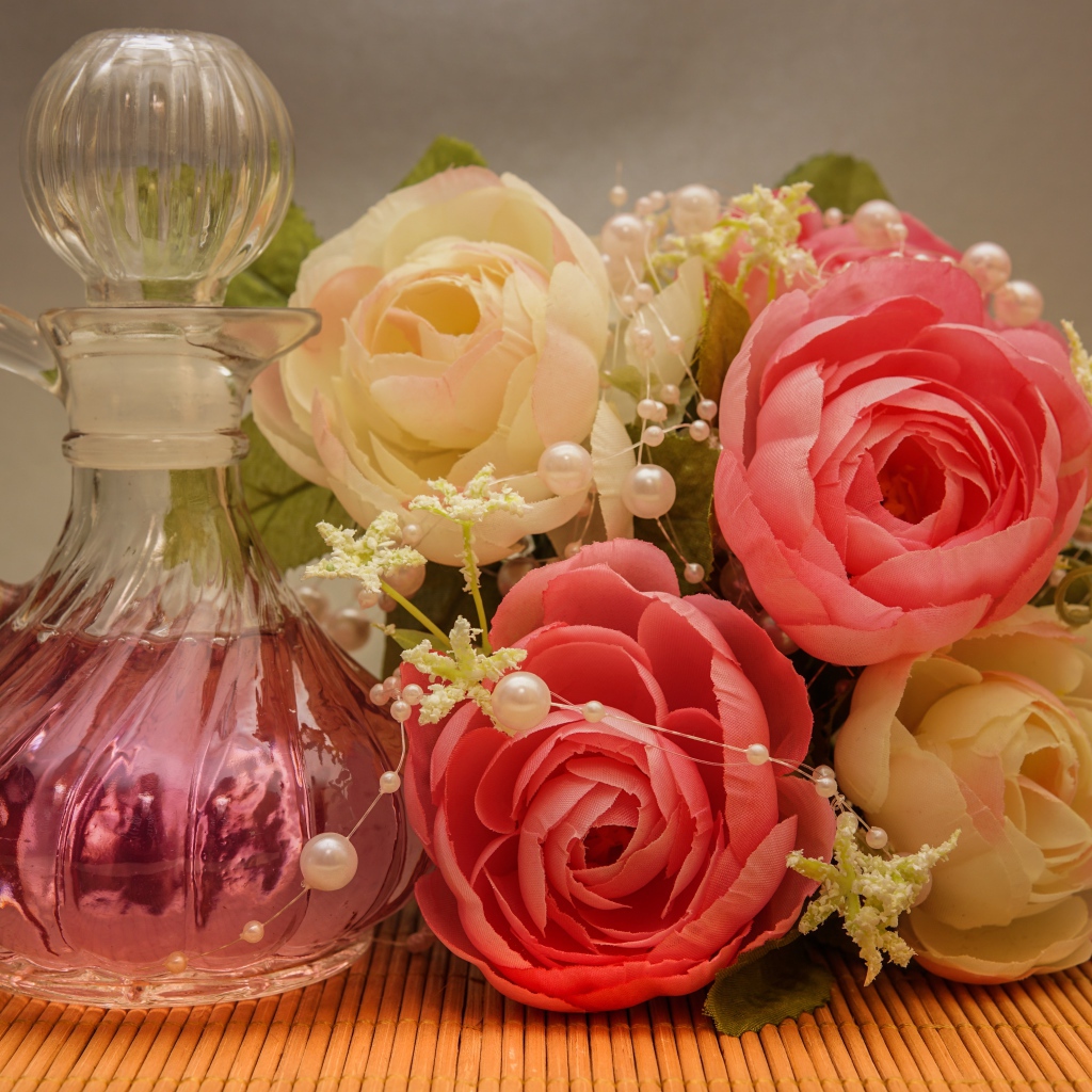 Красивый букет искусственных роз на столе с духами