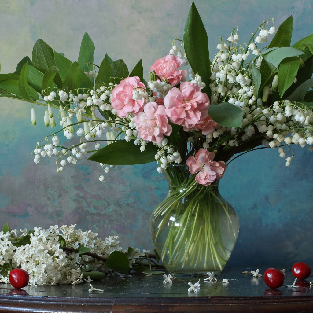 Красивый букет ландышей с розовыми цветами на столе с веткой сирени 