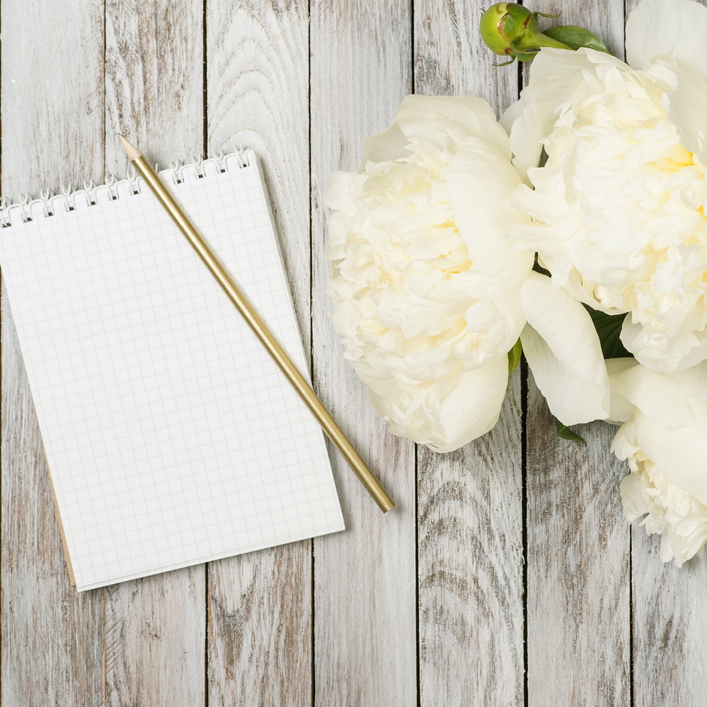 Букет белых пионов с блокнотом и ручкой на деревянном фоне 