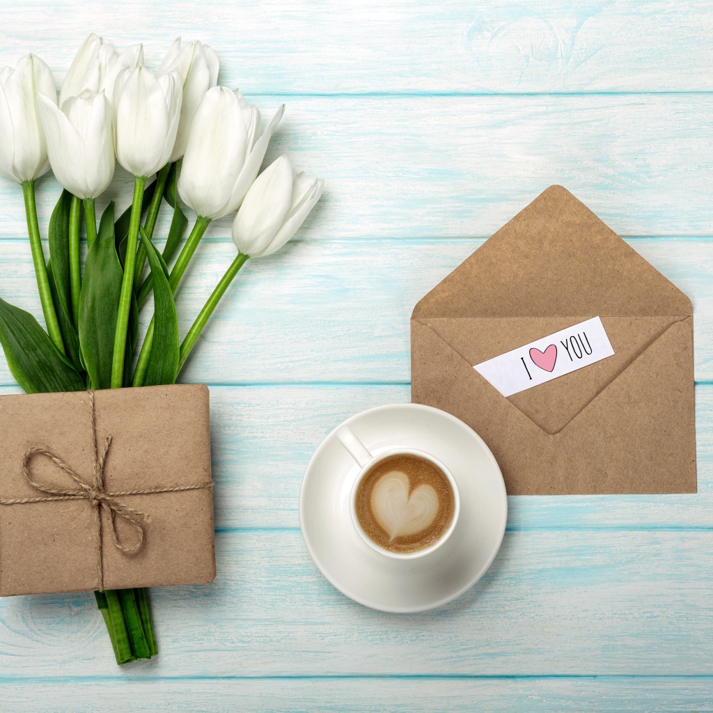 Букет белых тюльпанов на столе с подарком и чашкой кофе