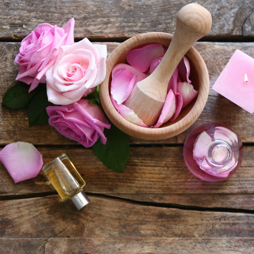 Лепестки розовой розы в ступке на столе с маслом