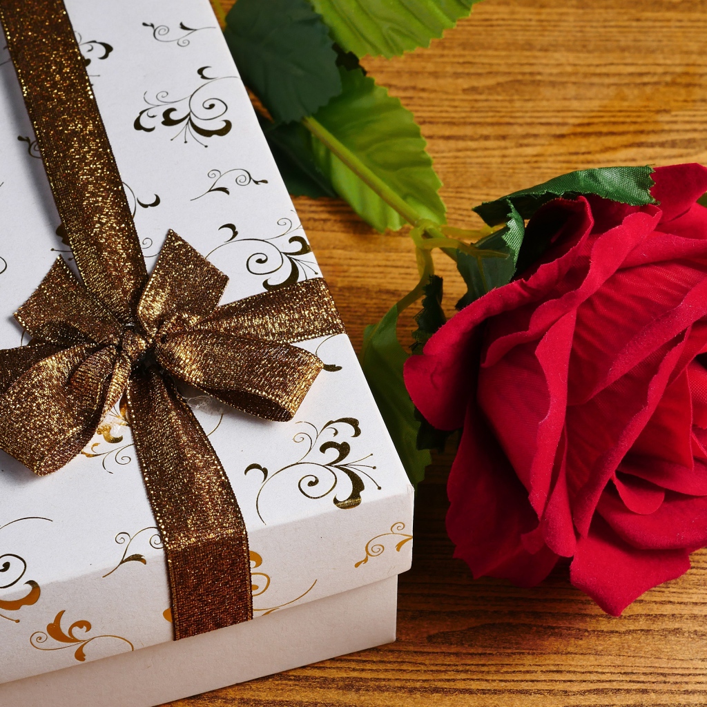 Красный цветок розы на столе с подарком