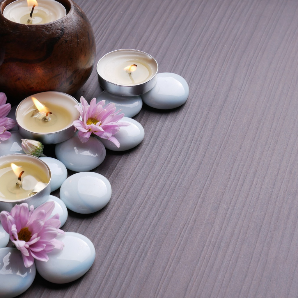 Камни с хризантемами и зажженными свечами на столе 