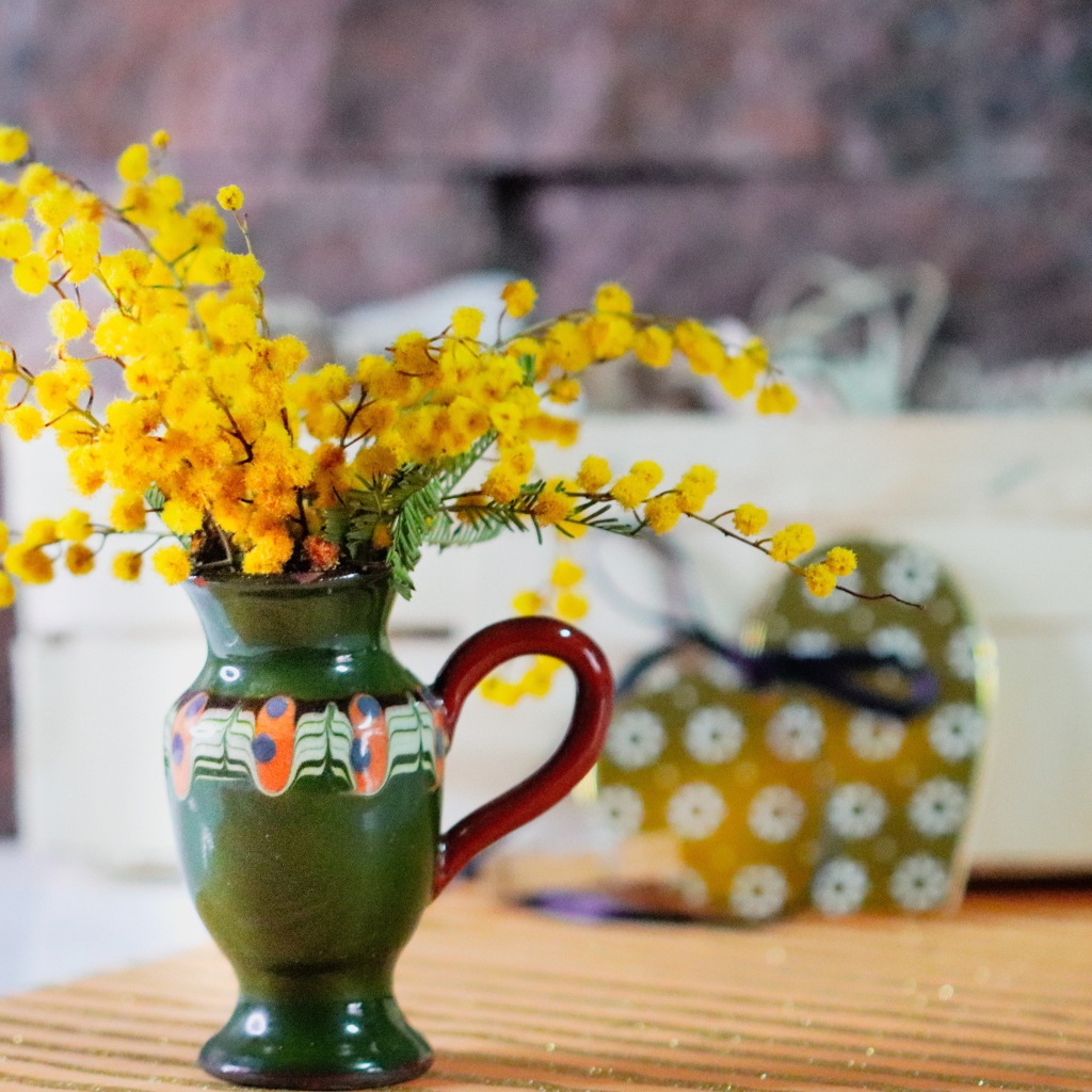 Желтые цветы мимозы в маленькой вазе на столе