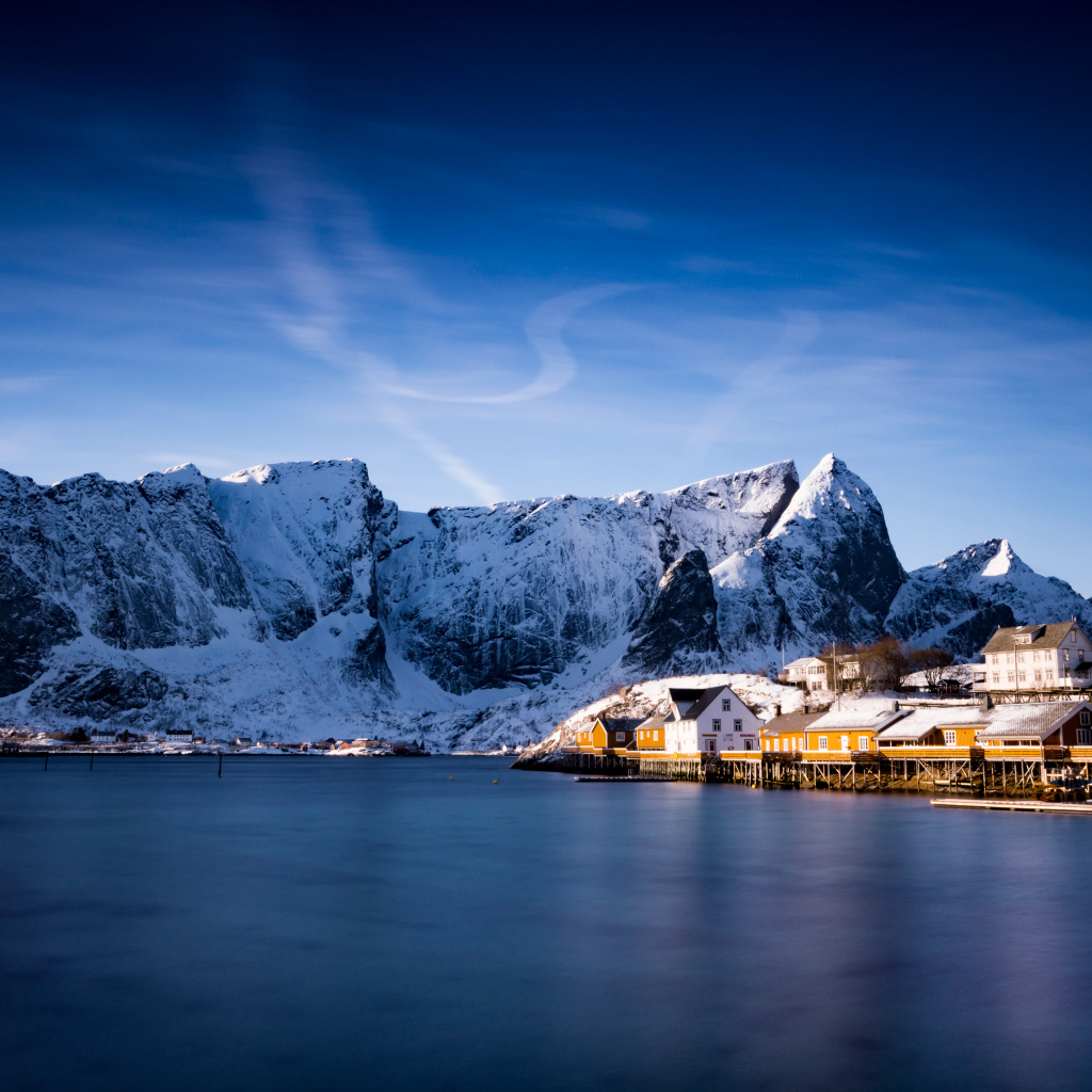 Красивый вид на дома у заснеженных гор под голубым небом 