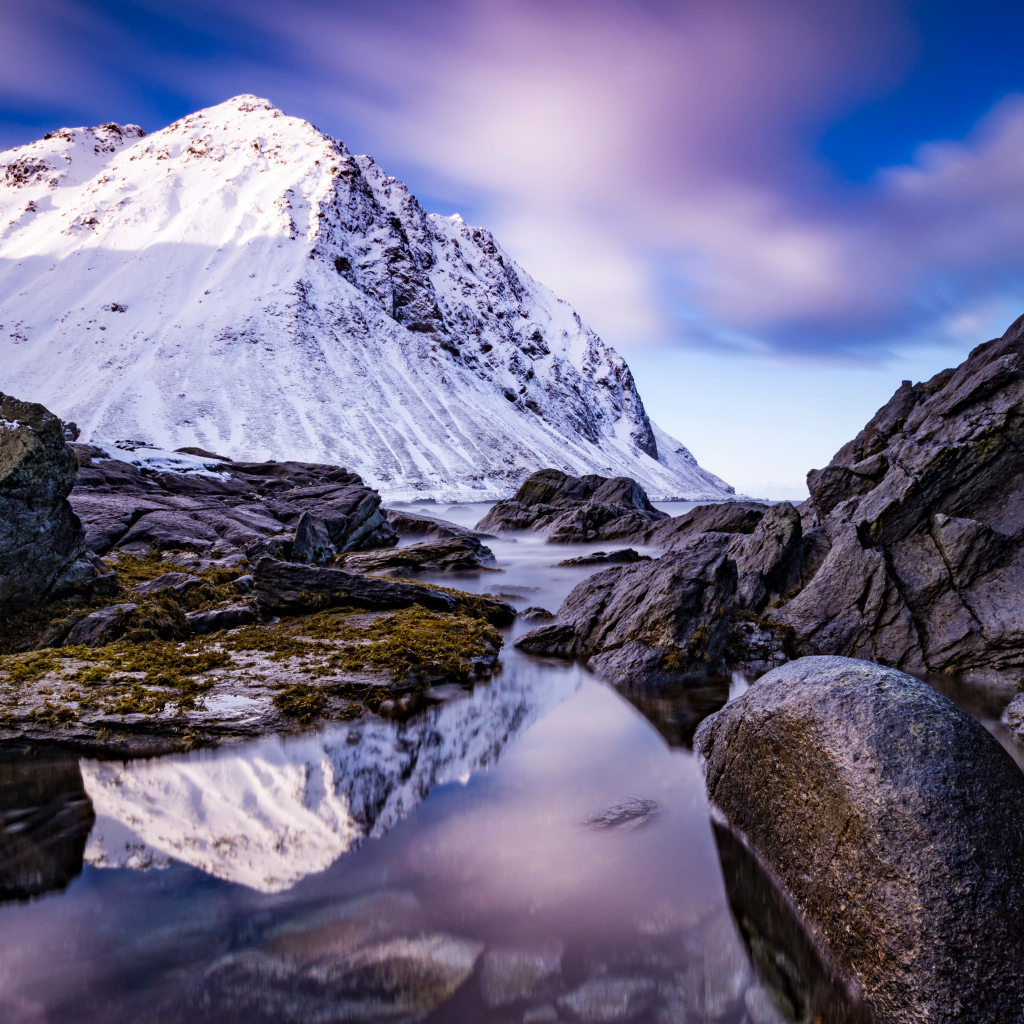 Заснеженные горы у ручья под красивым небом 