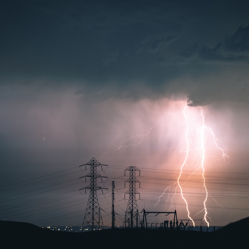 Яркая молния в небе над высоковольтной линией 