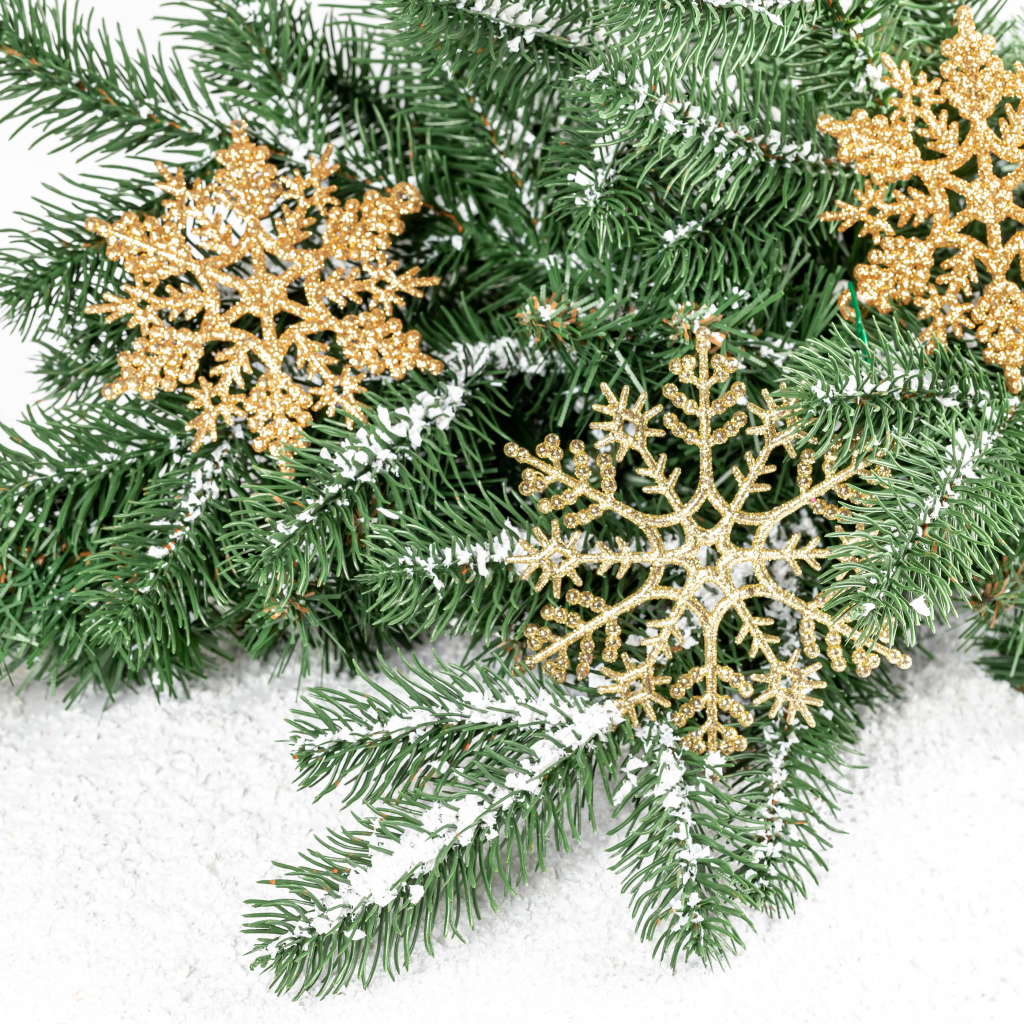 Золотистые снежинки и еловые ветки на снегу