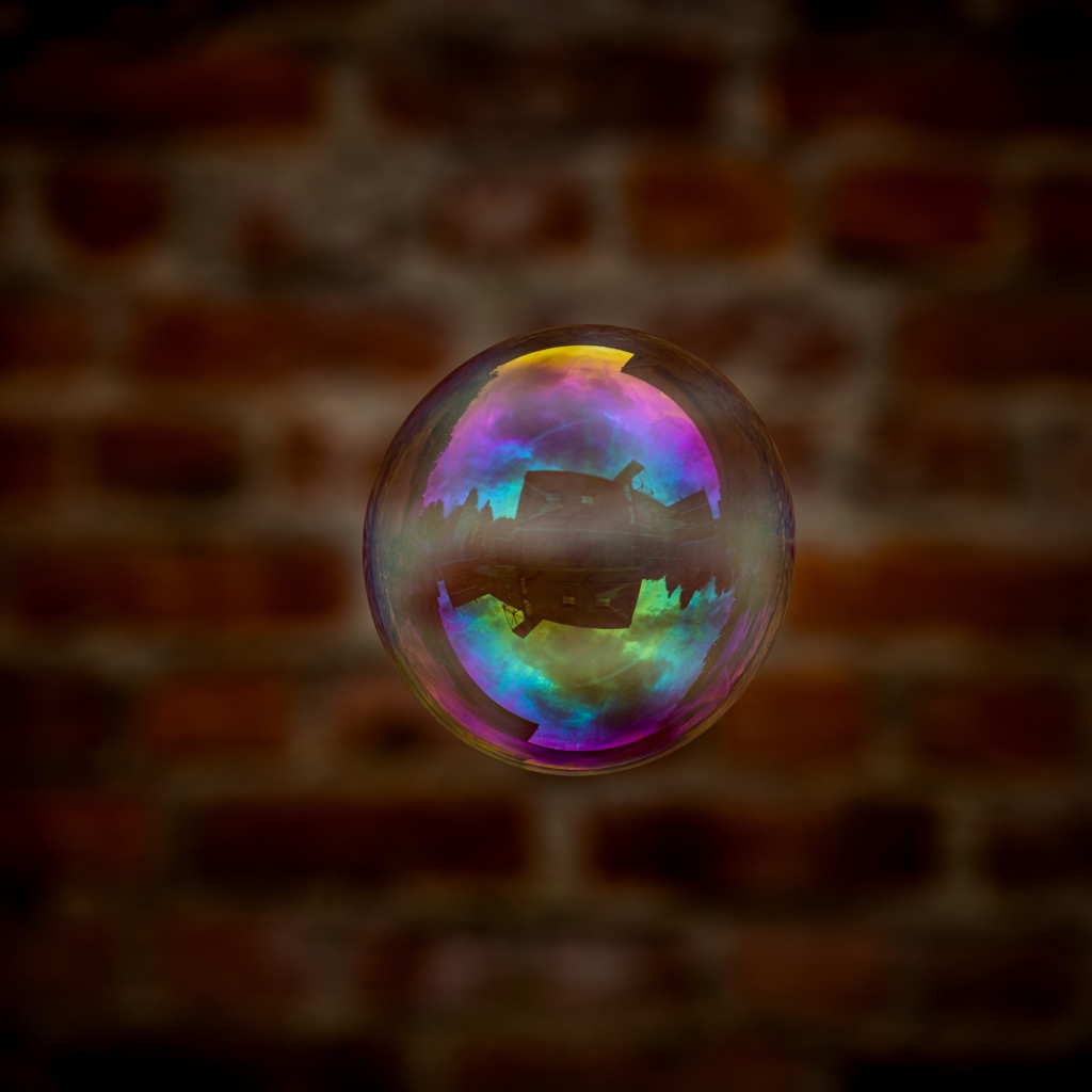 Мыльный пузырь в воздухе на фоне стены