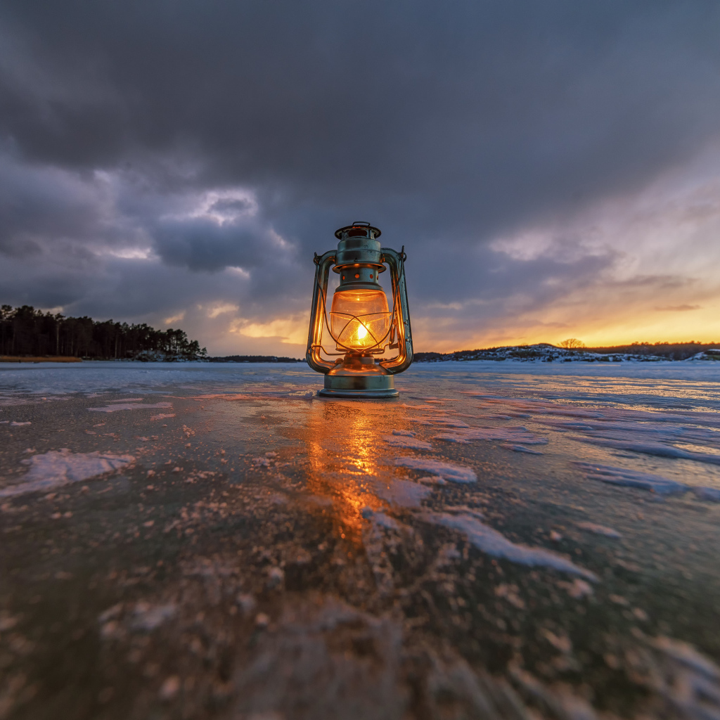 Керосиновая лампа стоит на покрытом льдом берегу