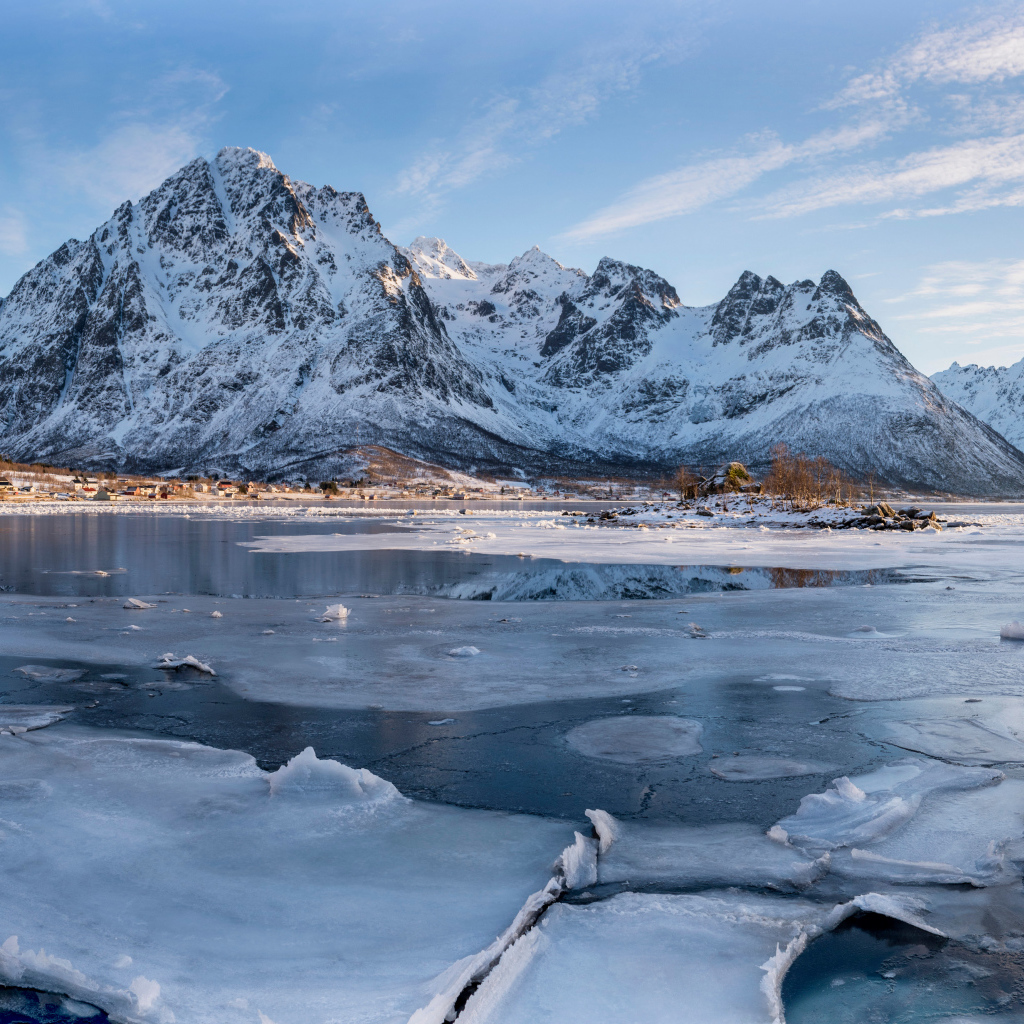 Покрытое льдом озеро у заснеженной горы