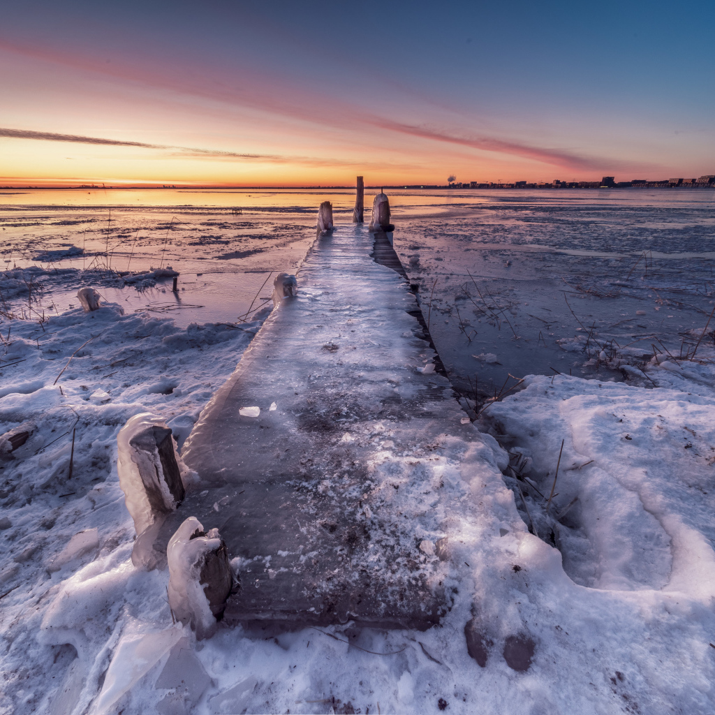 Покрытый льдом деревянный мост у озера 