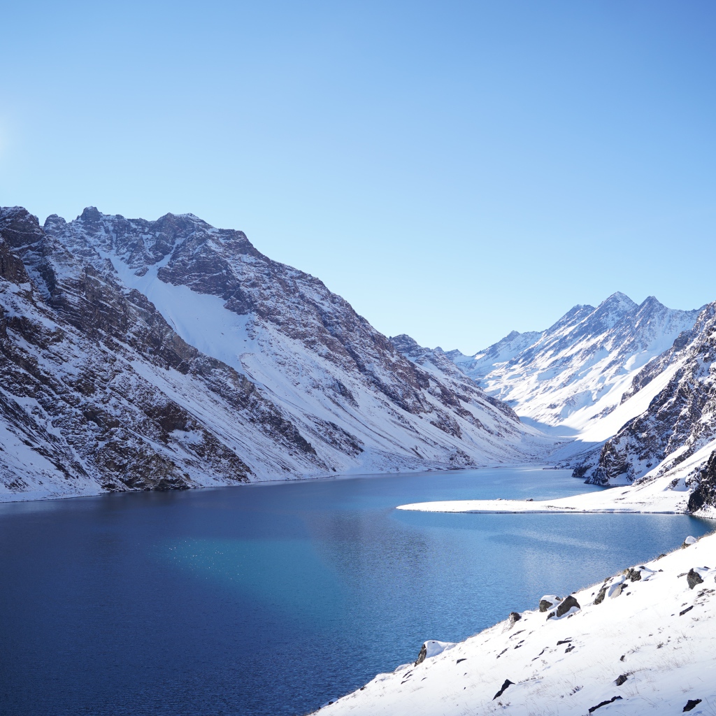 Озеро у покрытых снегом гор под голубым небом