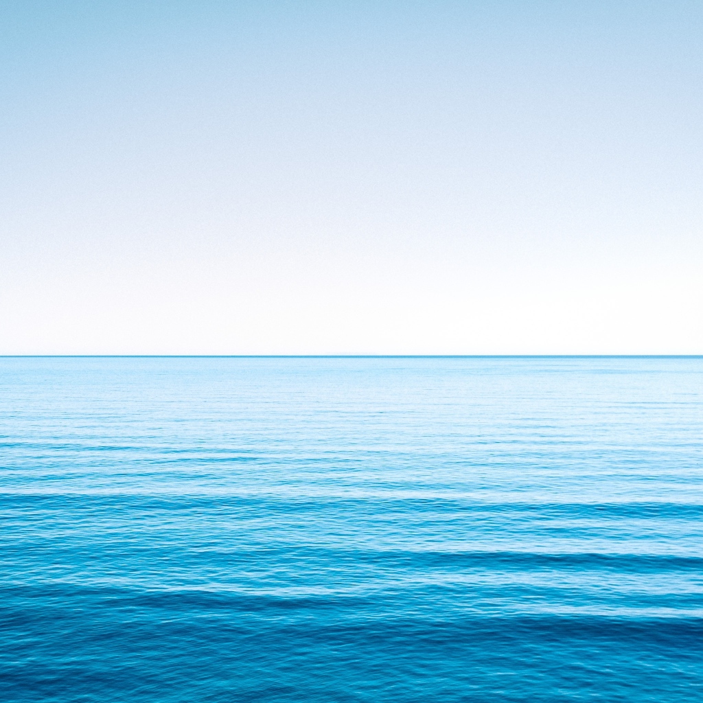 Спокойная голубая морская вода под голубым небом 