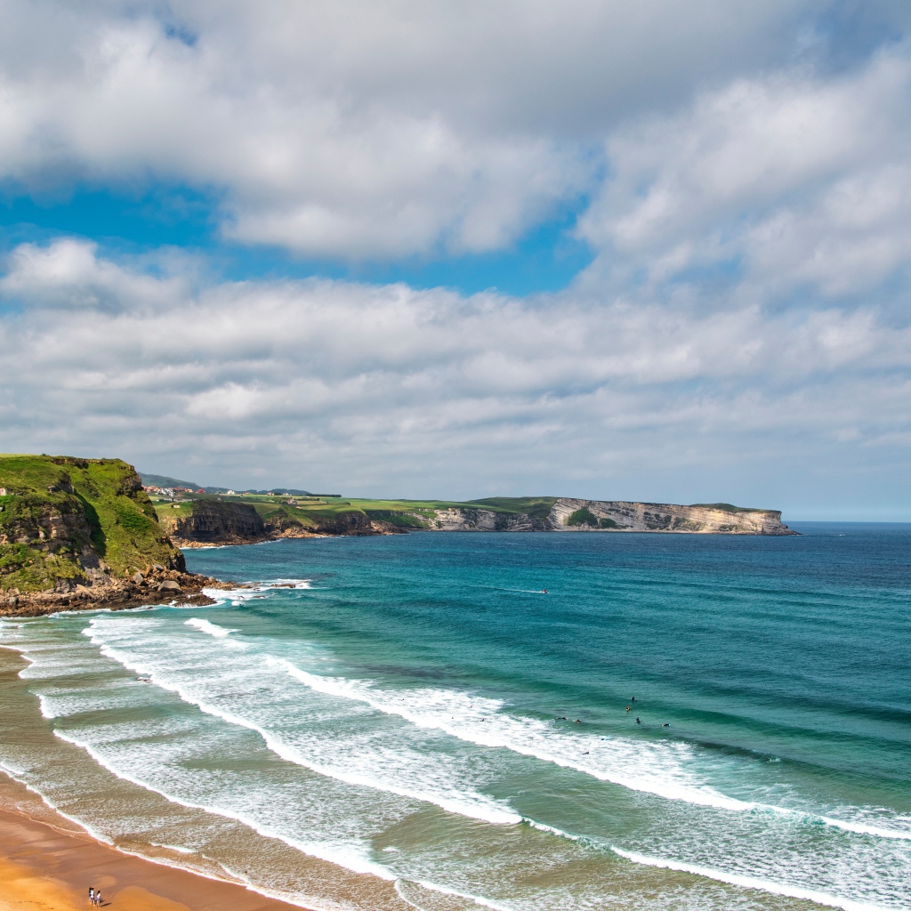 Спокойные волны на берегу залива под голубым небом с облаками