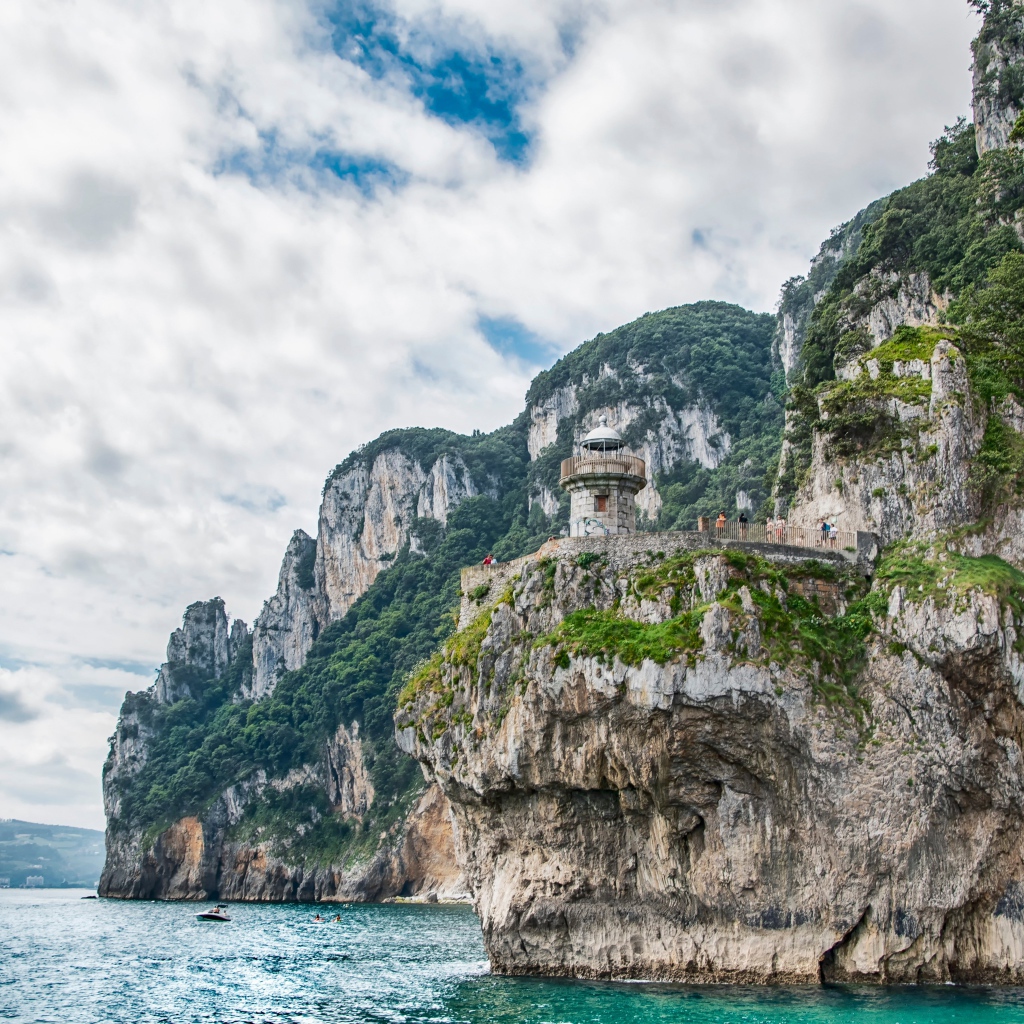 Высокие скалы у моря под белыми облаками 