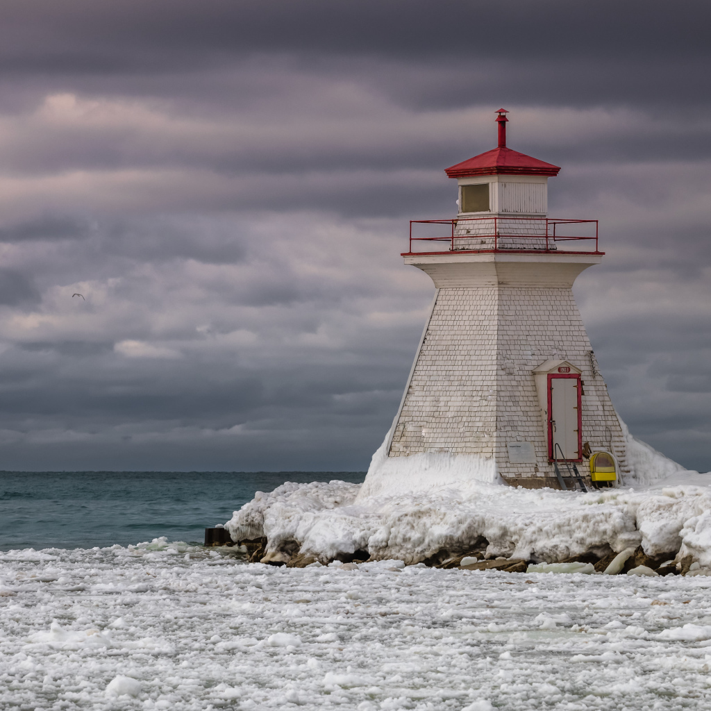 Маяк на покрытом льдом берегу у моря