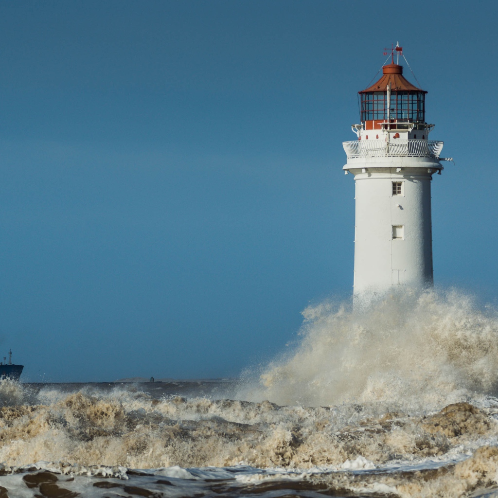Бушующие белые волны бьются о маяк 