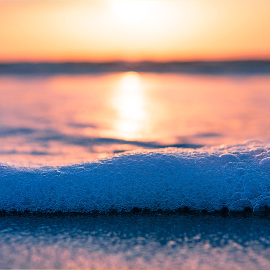 Белая морская пена с пузырям на закате