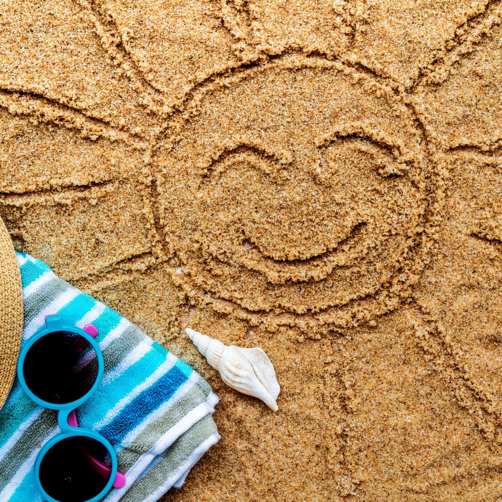 Нарисованное на песке солнце со шляпой и очками летом