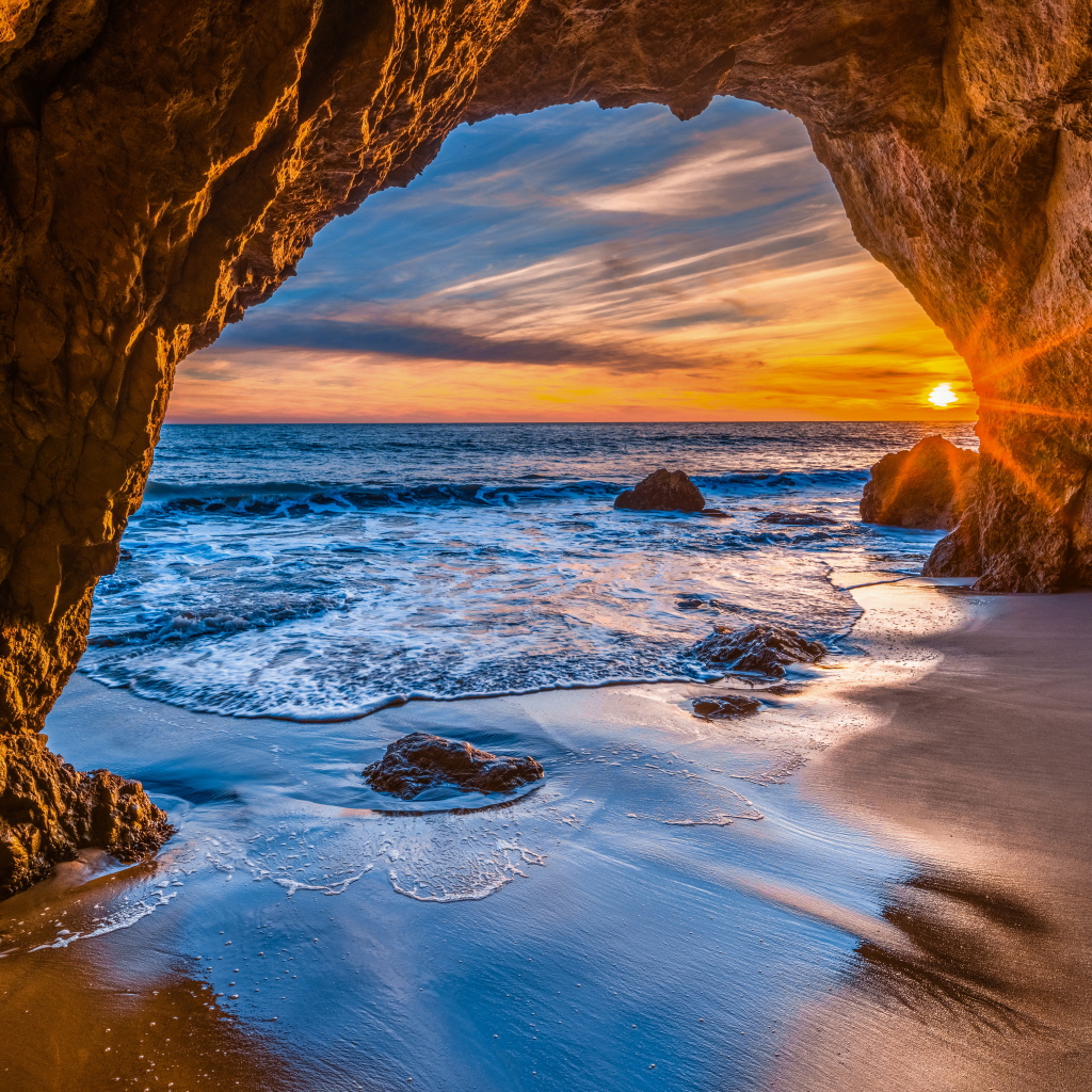Закат солнца в каменной арке в море