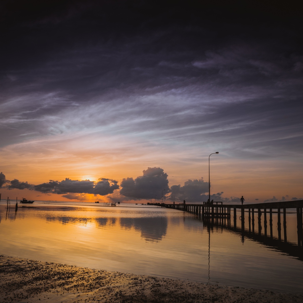 Деревянный мост на реке в лучах  солнца на закате