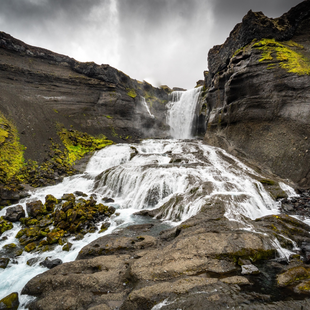 Быстрый горный водопад под серым небом