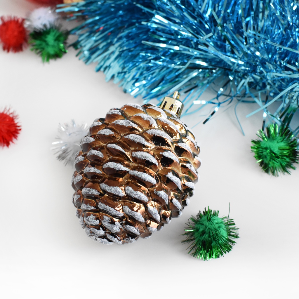 Елочная игрушка шишка с мишурой на белом фоне 