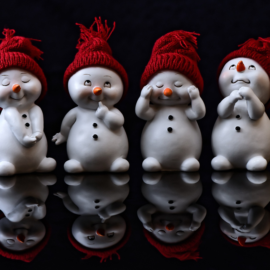 Маленькие статуэтки снеговики на черном фоне