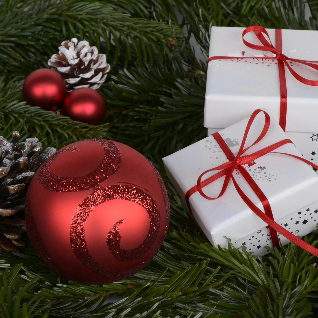 Два белых подарка, красный шар и еловая ветка на новый год 