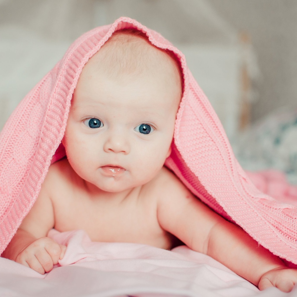 Грудной ребенок лежит под розовым пледом