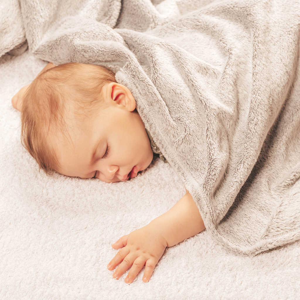 Грудной спящий ребенок под одеялом 