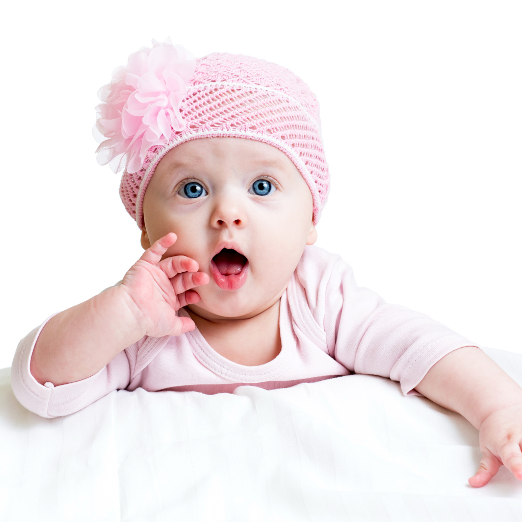 Красивая голубоглазая малышка в розовой шапке на белом фоне